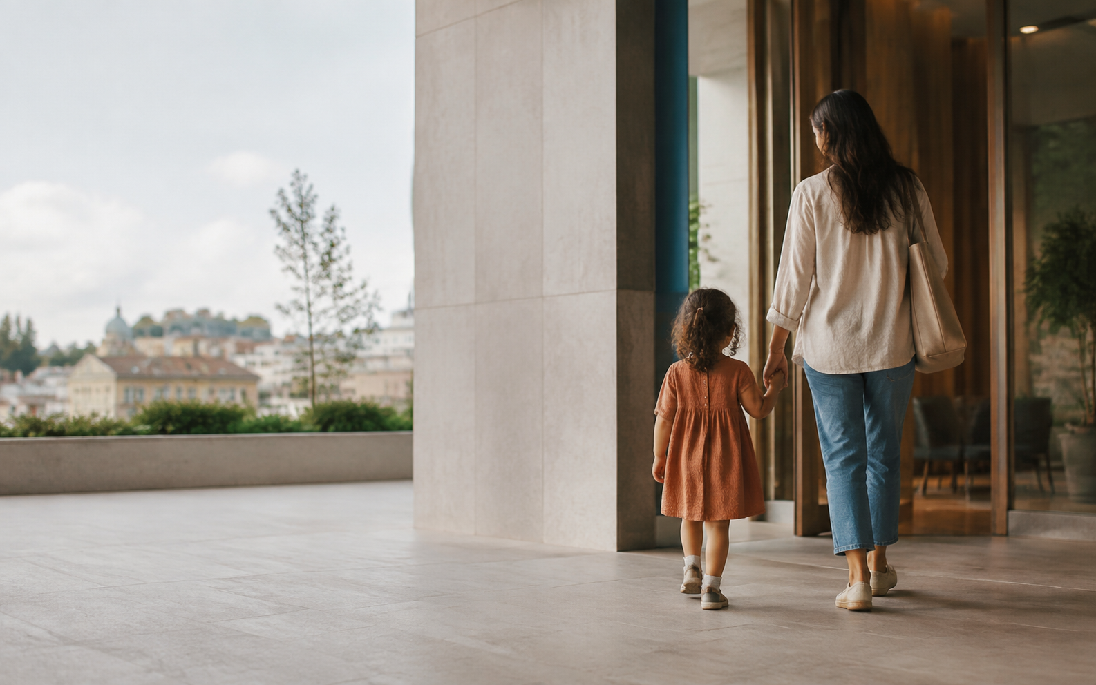 A parent and child walking together from a calm contemporary clinic entrance into soft daylight.